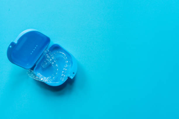 Clear dental aligners in a blue aligner container with a blue background.