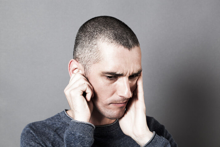 Man in pain due to a toothache and earache touching his jaw and ear