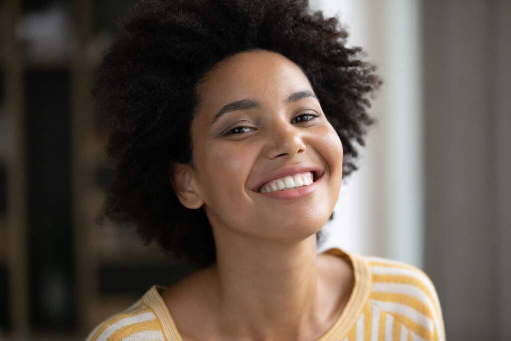 A young, pretty African American woman smiling broadly. 