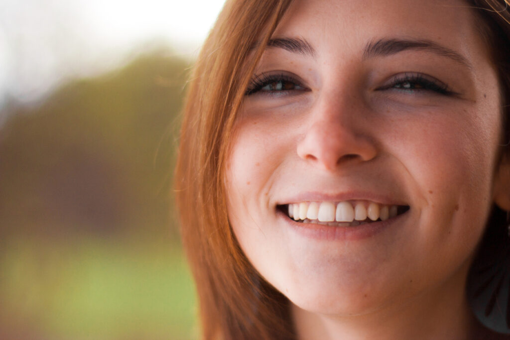 Beautiful young woman with auburn hair smiling broadly.