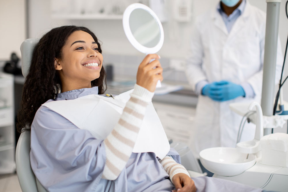 Woman smiling in mirror after composite bonding treatment