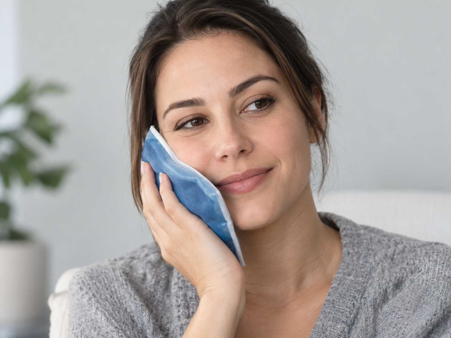 Woman holding a cold compress to her cheek to ease swelling while waiting to see an emergency dentist in Chicago